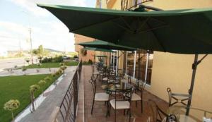 a patio with tables and chairs under green umbrellas at Pension Casa Grande in Baile Felix