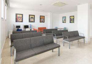 a waiting room with gray couches and chairs at Albergue Inturjoven Chipiona in Chipiona