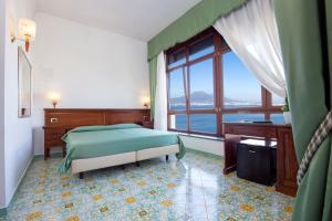 a bedroom with a bed and a large window at La Panoramica Hotel in Castellammare di Stabia