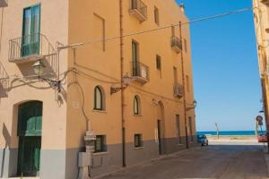 a yellow building on a street next to the ocean at Campo Appartamenti in Trapani