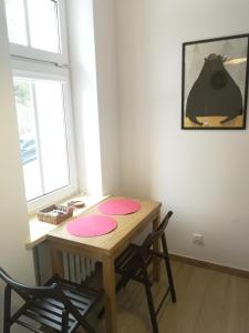 a dining room table with two chairs and two windows at Apartament Parkowy in Duszniki Zdrój