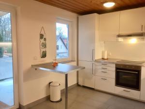 une cuisine avec des placards blancs, une table et une fenêtre dans l'établissement Ferienwohnung im Zentrum, à Bad Schwartau