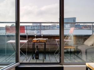 a table and chairs on a balcony with a bottle of wine at Edville Studio Riverside in Ghent