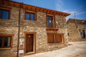 una casa de piedra con un balcón en un lateral. en El Bulin de Paredes, en Paredes de Buitrago