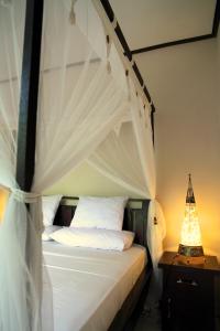 a bedroom with a canopy bed with white pillows at Latugu Homestay Ubud in Ubud