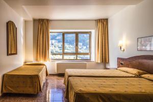 a hotel room with two beds and a window at Hotel Cervol in Andorra la Vella