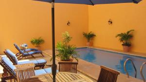 a pool with an umbrella and chairs and a table with at Castelmar Hotel in Campeche