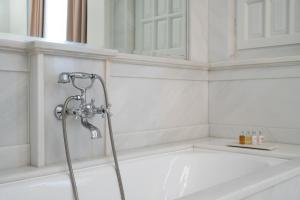 a bath tub with a shower head in a bathroom at Noble Suites in Athens