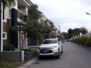ein weißes Auto, das auf einer Straße neben Gebäuden parkt in der Unterkunft Asaby Homestay Yogya in Yogyakarta