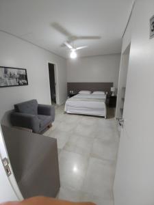 ein Schlafzimmer mit einem Bett und einem Sofa in einem Zimmer in der Unterkunft Hotel Ouro Verde in Três Pontas