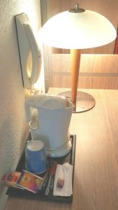 una mesa con aseo, una lámpara y una revista en Doubs Hotel - Besançon Ecole Valentin, en Besançon
