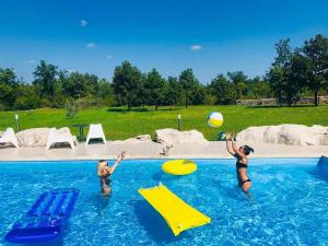 dos niños jugando con una pelota en una piscina en Stancija Negričani, en Divšići