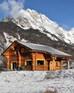 a log cabin in front of a snow covered mountain at L'Etoile du Berger in Saint-Martin-de-la-Porte
