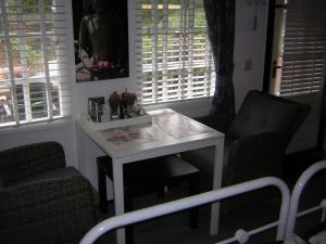 een witte tafel en 2 stoelen in een kamer met ramen bij Prive tuinhuis B&B Elly in Sint Pancras