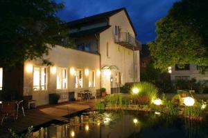 uma casa com um lago em frente à noite em Hotel ZweiLinden Meckenheim Bonn em Meckenheim