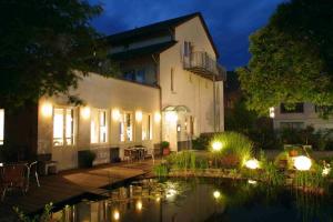a house with a pond in front of it at night at Hotel ZweiLinden Meckenheim Bonn in Meckenheim
