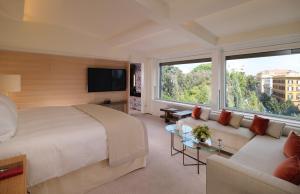 a hotel room with a large bed and a couch at Hotel Eden - Dorchester Collection in Rome