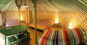 a room with two beds and a table in a yurt at Yourtes Mongoles Gavarnie in Gèdre