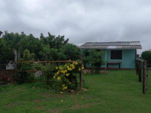 a house with a gate with yellow flowers in a yard at Chale na praia in Xangri-lá
