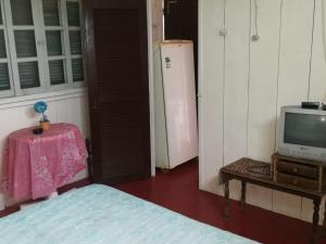 a room with a bed and a tv and a table at Chale na praia in Xangri-lá