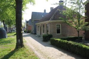 een stenen huis met een boom naast een straat bij 't Stee fan Anne P. in Rottevalle