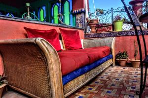 a wicker bench with red pillows on a balcony at Riad Razoli Sidi Fateh in Rabat