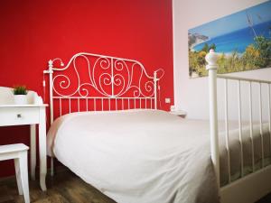 una camera con letto bianco e pareti rosse di B&B Vivere il Mare a Numana