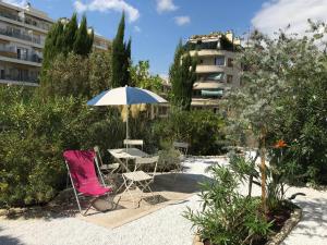 - une table, deux chaises et un parasol dans la cour dans l'établissement Villa le Nid, à Nice