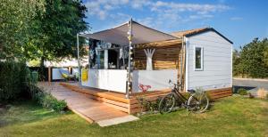 uma pequena casa com um deque e uma bicicleta em Camping l'Ile aux Oiseaux em LʼÎle-dʼOlonne