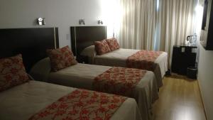 um quarto de hotel com duas camas e uma cadeira em Palermo Bridge em Buenos Aires