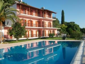 a hotel with a swimming pool in front of a building at Aronis Apartments in Benitses
