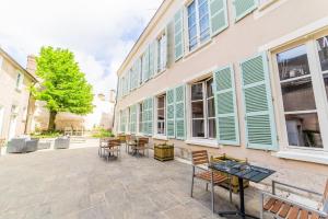 un patio avec des tables et des chaises à côté d'un bâtiment dans l'établissement Hôtel Particulier de Champrond, à Chartres