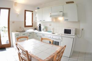 a white kitchen with a table and a microwave at Les Coquillages in Mimizan-Plage