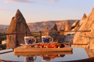 a tray of fruit on a table with two cups at Village Cave House Hotel in Goreme