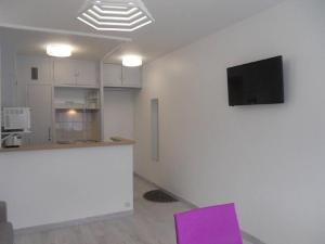 a kitchen with purple chairs and a tv on a wall at La Forêt 5 in Mimizan-Plage