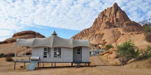 a house in the middle of a desert with a mountain at Spitzkoppen Lodge in Usakos