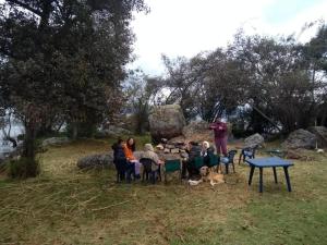 a group of people sitting around a table with a dog at Camping Los Balcones in Cuítiva