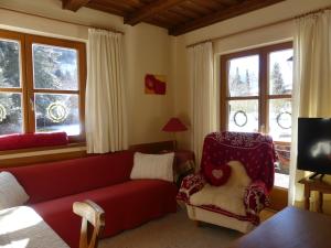 sala de estar con sofá rojo y silla en Ferienwohnungen Familie Wetzlinger, en Bad Kleinkirchheim