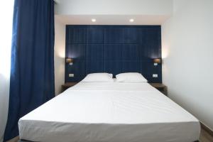 a large white bed in a room with blue curtains at Hotel Tau in Međugorje