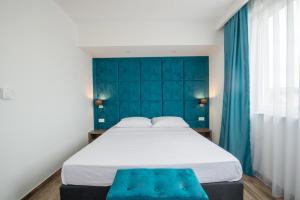 a bedroom with a large bed with a blue headboard at Hotel Tau in Međugorje