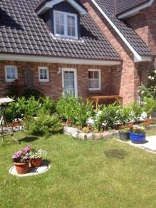 une maison avec une cour ornée de fleurs et de plantes dans l'établissement Mittelreihenhaus Carla - Sylt, Westerland, à Tinnum