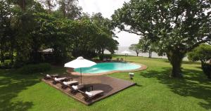 una piscina con tumbonas y sombrilla en Puerto Valle Hotel de Esteros en Puerto Valle