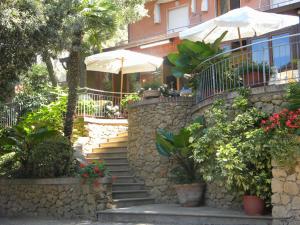 a house with a stone wall and stairs in front at Hotel Rosa Del Tirreno in Quercianella