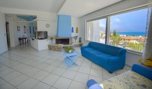 un soggiorno con divano blu e una grande finestra di Villa Trinacria Apartments ad Alcamo Marina