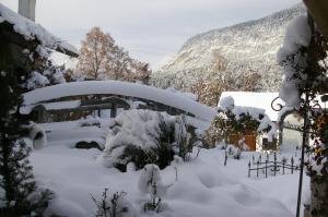 einen schneebedeckten Hof mit Bäumen und einem Haus in der Unterkunft Thalerhof in Roppen