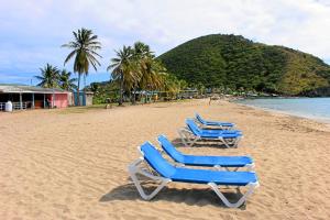 two blue lounge chairs sitting on a beach at CosyNest in Basseterre