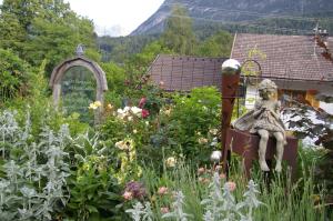 um jardim com uma estátua no meio das flores em Thalerhof em Roppen