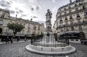 a statue in the middle of a street with buildings at Lafayette Private Apartment in Paris