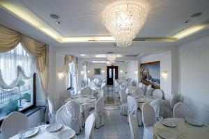 カステッランマーレ・ディ・スタービアにあるLa Panoramica Hotelの白いテーブルと椅子、シャンデリアのあるレストラン