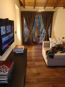 uma sala de estar com um sofá e uma televisão de ecrã plano em Rose Cottage Tuscany em Fosdinovo